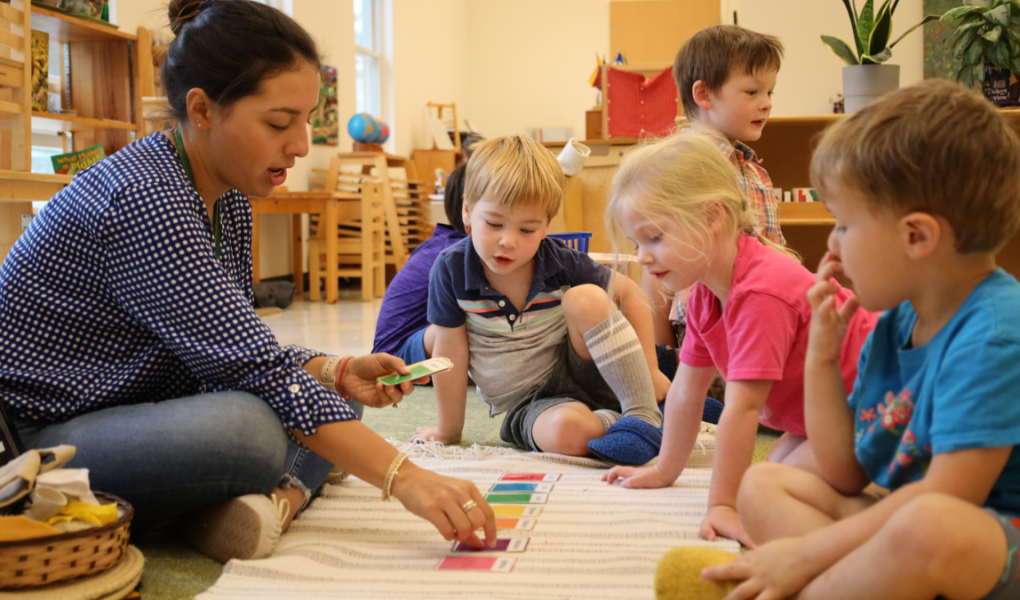 A Montessori teacher engages children in a colorful card activity, fostering learning and creativity in a vibrant classroom setting.