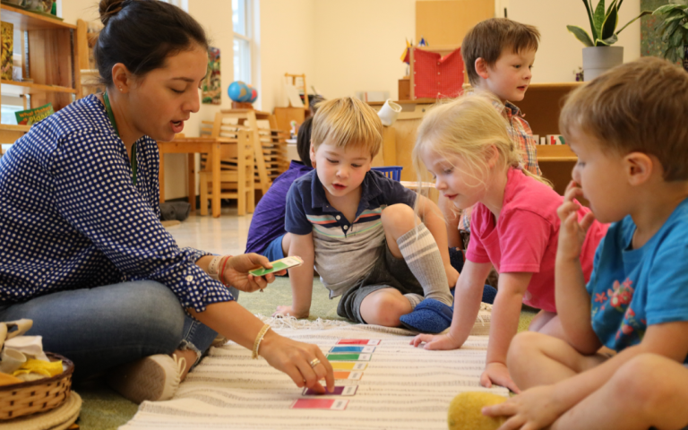 A Montessori teacher engages children in a colorful card activity, fostering learning and creativity in a vibrant classroom setting.